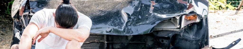 Man crying on his old damaged car after crash accident